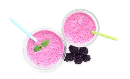Glasses of blackberry smoothie and berries on white background, top view