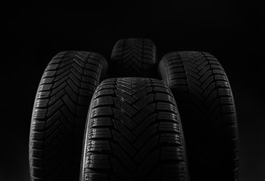 Set of new winter tires on black background, closeup