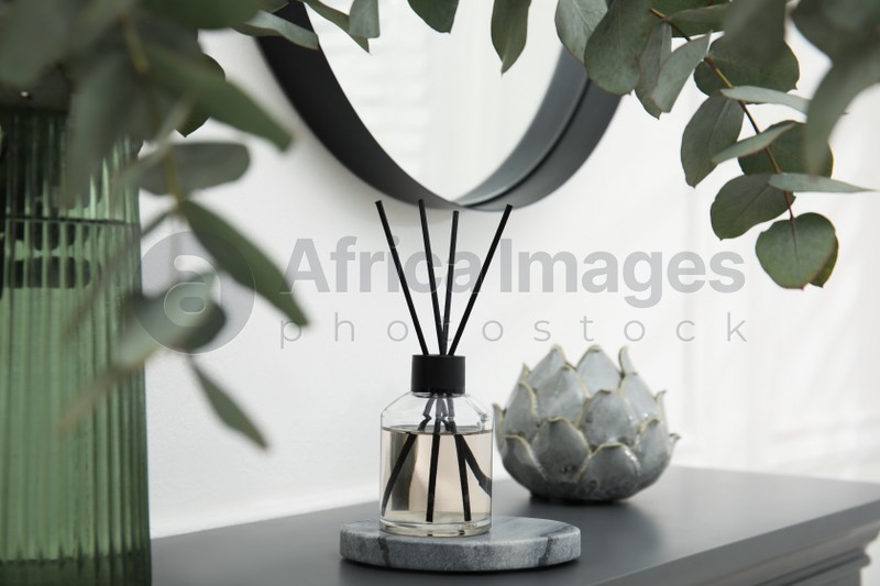 Reed diffuser and home decor on grey table near white wall