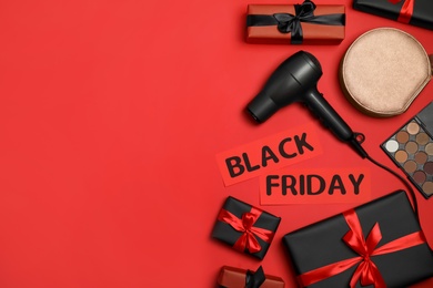 Gift boxes, cosmetics, bag, hairdryer and phrase Black Friday on red background, flat lay. Space for text