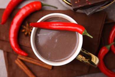 Photo of Cup of hot chocolate with chili pepper on grey table, flat lay