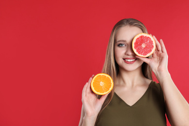 Photo of Young woman with cut orange and grapefruit on red background, space for text. Vitamin rich food