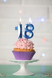 18th birthday. Delicious cupcake with number shaped candles for coming of age party on turquoise table