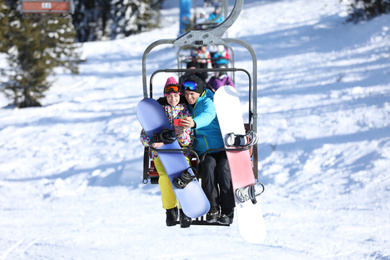 Couple taking selfie while lifting at mountain ski resort. Winter vacation