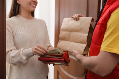 Woman giving tips to deliveryman indoors, closeup