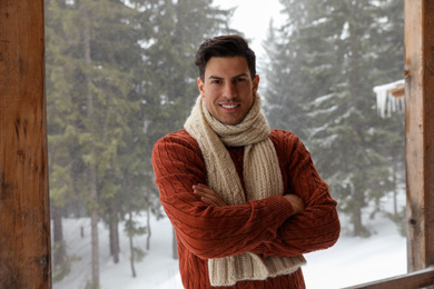 Handsome man wearing warm sweater and scarf outdoors on snowy day. Winter season