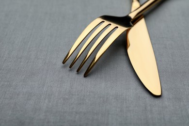 Golden fork and knife on grey table, closeup