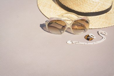 Stylish hat, sunglasses and jewelry on grey surface, space for text