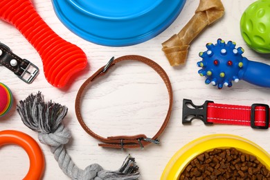 Flat lay composition with dog collar, toys and food on white wooden table