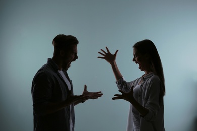 Silhouette of couple having argument on color background. Relationship problems