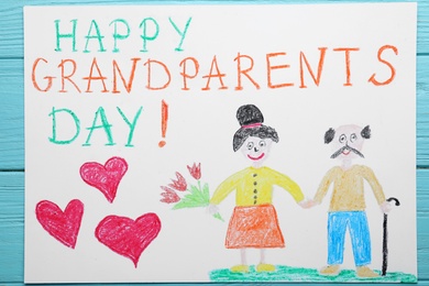 Beautiful drawing with phrase Happy Grandparents Day on blue wooden table, top view