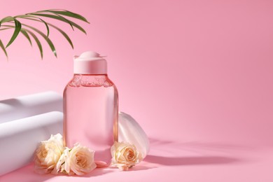 Bottle of micellar water, roses and cotton pads on pink background. Space for text
