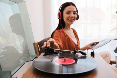 Woman listening to music with turntable at home, focus on hand
