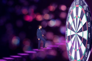Businessman stepping up on stairs to empty dart board against blurred background
