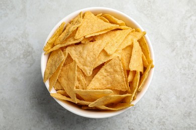 Photo of Bowl with tasty tortilla chips (nachos) on grey table, top view