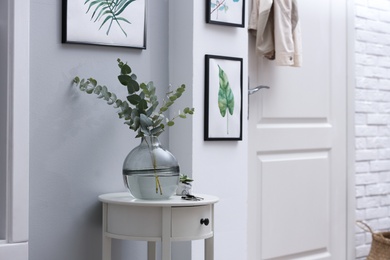 Vase with fresh eucalyptus branches on table in entryway. Interior design