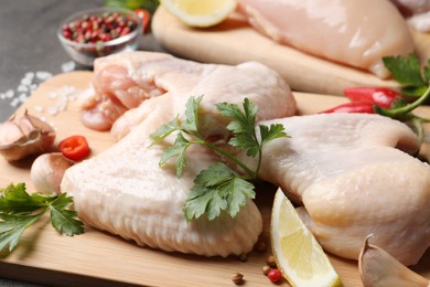 Fresh raw chicken wings and other products on wooden board, closeup