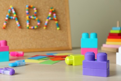 Photo of Cork board with abbreviation ABA (Applied behavior analysis) at table, focus on colorful blocks