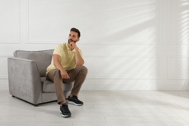 Photo of Man sitting in armchair near white wall, space for text