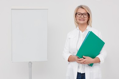 Photo of Professional doctor wearing medical coat near flipchart board in clinic