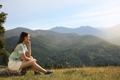 Young woman enjoying beautiful mountain landscape on sunny day