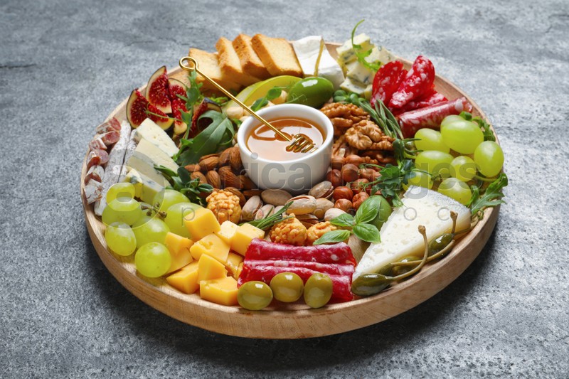 Wooden platter with different tasty appetizers on grey table