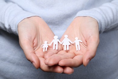 Photo of Woman holding paper family figures, closeup. Insurance concept