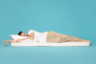 Man sleeping on soft mattress against light blue background
