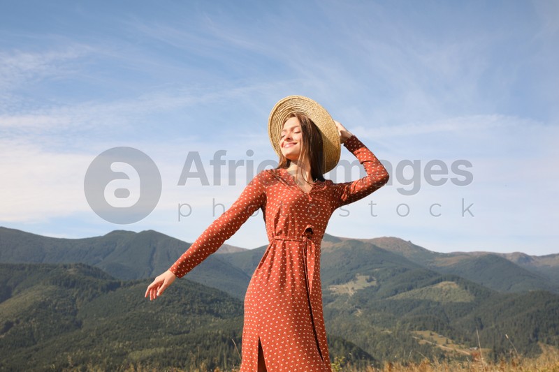 Photo of Young woman with straw hat walking in beautiful mountains on sunny day