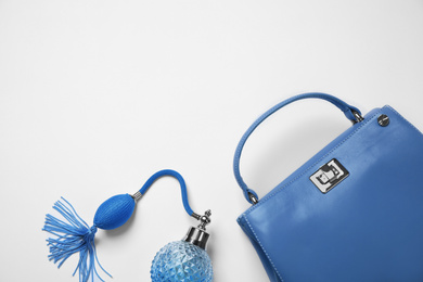 Photo of Stylish purse and perfume bottle on white background, top view. Classic blue - color of the Year 2020