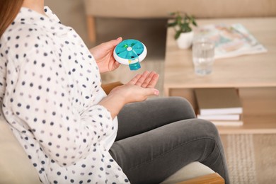 Pregnant woman taking pill from container at home, closeup