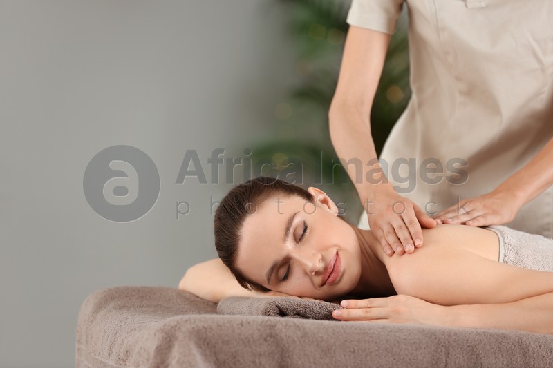 Photo of Beautiful young woman enjoying massage in spa salon. Space for text