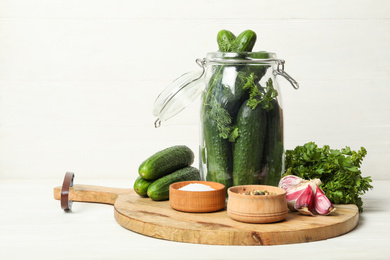 Pickling jar with fresh ripe cucumbers and spices on white wooden table