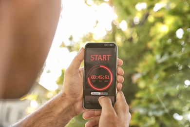 Man using fitness app on smartphone outdoors, closeup