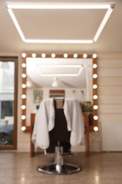 Blurred view of hairdressing salon with large mirror and chair