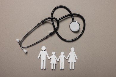 Paper family figures and stethoscope on light grey background, flat lay. Insurance concept