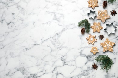 Tasty Christmas cookies, cutters and fir branches on white marble table, flat lay. Space for text