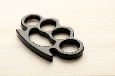 Black brass knuckles on white wooden background, closeup