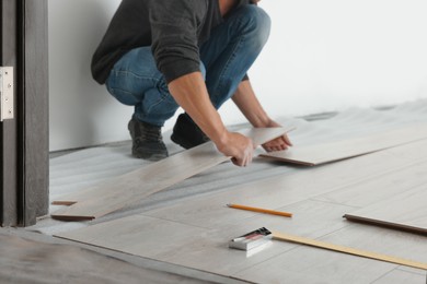 Photo of Worker installing new laminate flooring in room, closeup