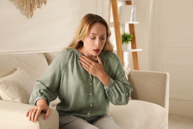 Young woman suffering from pain during breathing at home