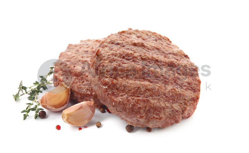 Tasty grilled hamburger patties with seasonings on white background