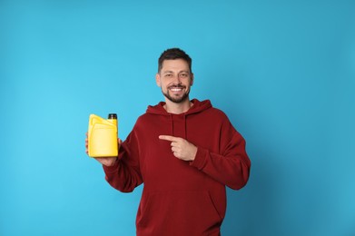 Man pointing at yellow container of motor oil on light blue background