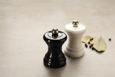 Photo of Wooden salt and pepper shakers with bay leaves on light table, closeup. Spice mill
