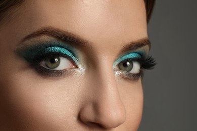 Young woman with evening makeup on grey background, closeup. Eye shadow product
