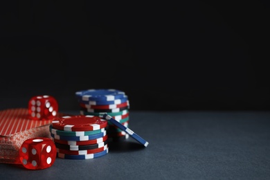 Poker chips, cards and dices on dark background, space for text