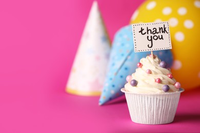 Tasty cupcake with Thank You note and paper cones on pink background, space for text