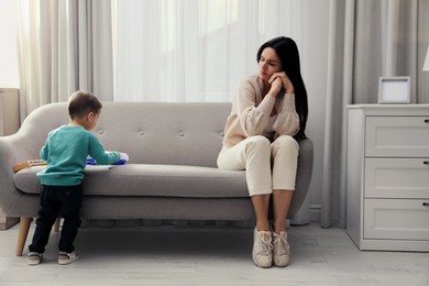 Depressed single mother with child in living room