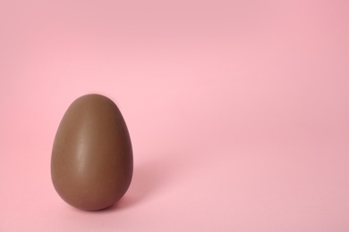 Sweet chocolate egg on pink background. Space for text
