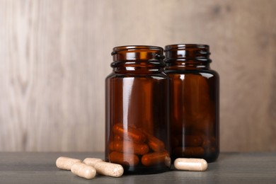 Gelatin capsules and bottles on wooden table
