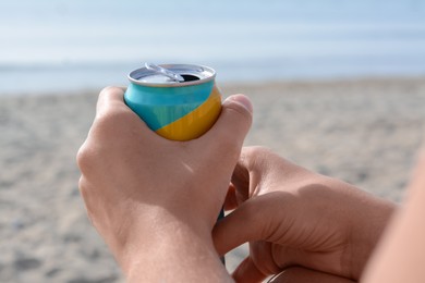 Photo of Woman holding aluminum can with beverage on beach, closeup
